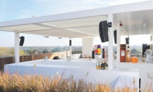 A white metal pergola being used as a beautiful garden bar. 