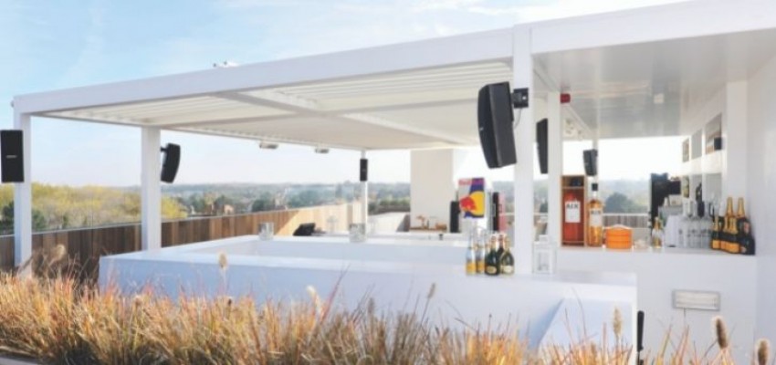 A white metal pergola being used as a beautiful garden bar. 